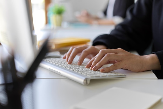 Cropped image of a worker working on pc computer typing on keyboard in the office