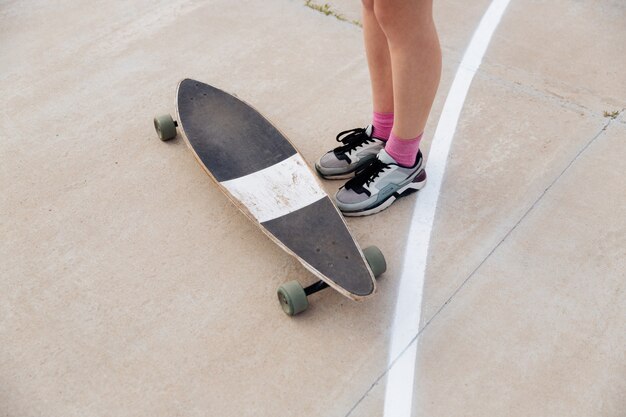 Cropped image of young female legs and skateboard outdoors over white