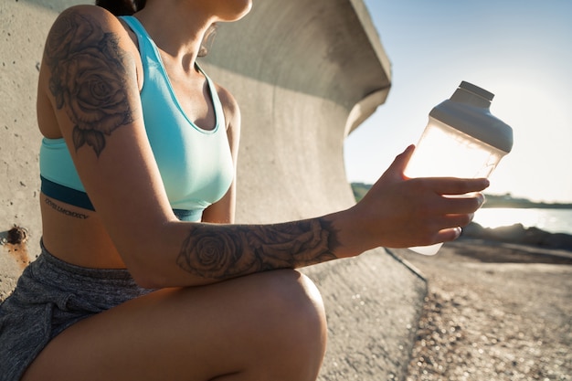 Cropped image of a young fitness woman sitting and resting