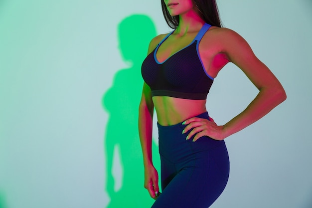 Cropped image of young sports woman posing isolated with led flash lights.