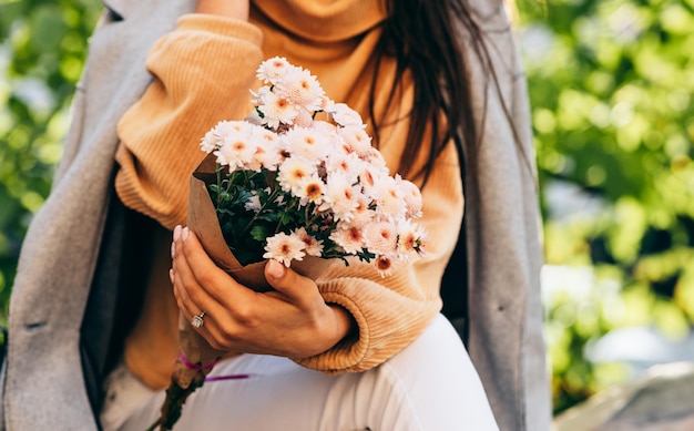 Cropped image of young woman with bouquet of pink flowers on sunny day in the park Pretty female recieved a gift from her boyfreind in the city street Woman's day