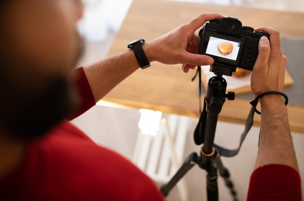 Cropped of male photographer holding camera taking photo of hamburger