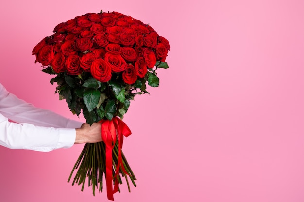 Foto le braccia tagliate dell'uomo tengono grandi cento rose rosse luminose