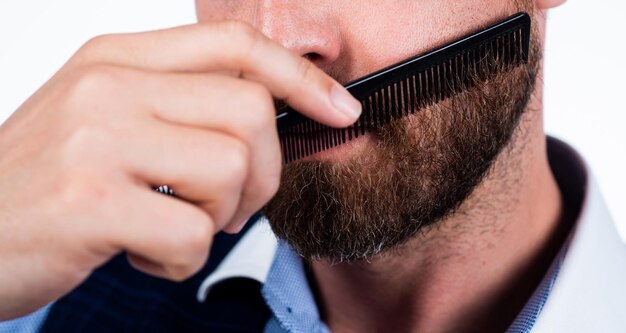 Cropped man comb his beard with hair brush barber