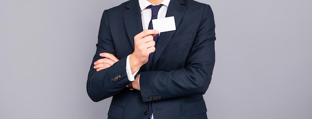 Cropped man in suit showing business card with copy space contact me