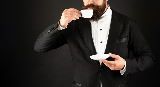 Cropped man in tuxedo bow tie with coffee cup gentleman drink coffee on black background