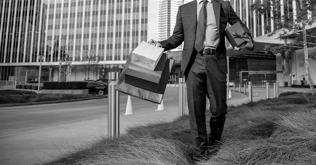 Cropped man with shopping bags and present box walking outside the office copy space discount