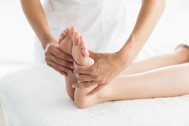 Cropped masseur giving foot massage to woman