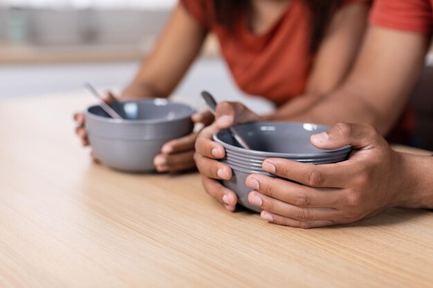 Cropped millennial african american man and woman hold in hands empty plates at table in kitchen close up