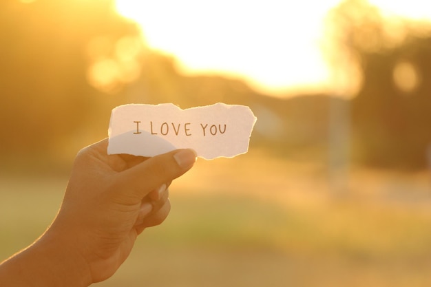 Photo cropped of person holding paper with i love you text