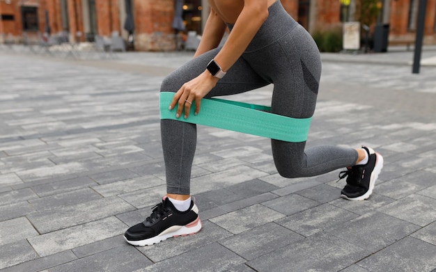 Cropped photo of athletic woman doing lunges exercise with resistance elastic band