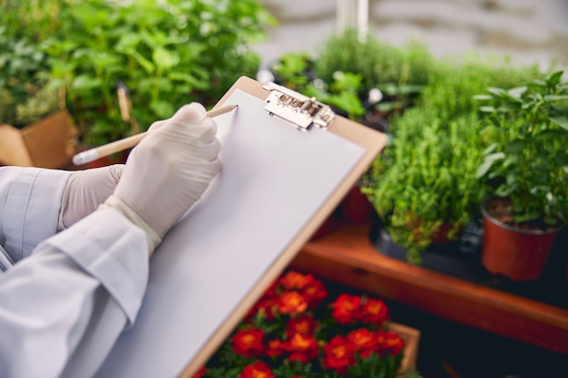 Cropped photo of a biological scientist holding a clipboard and a pencil with both hands