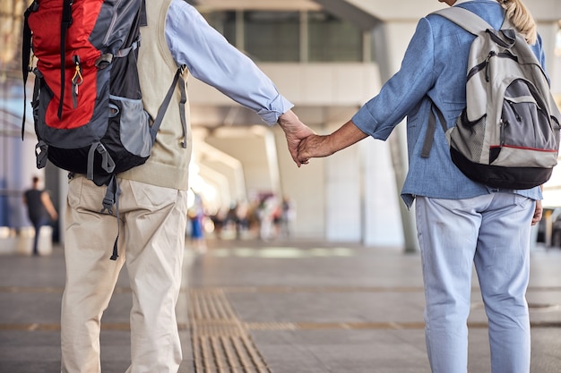 Cropped photo of a Caucasian woman with a ponytail and her male spouse holding hands