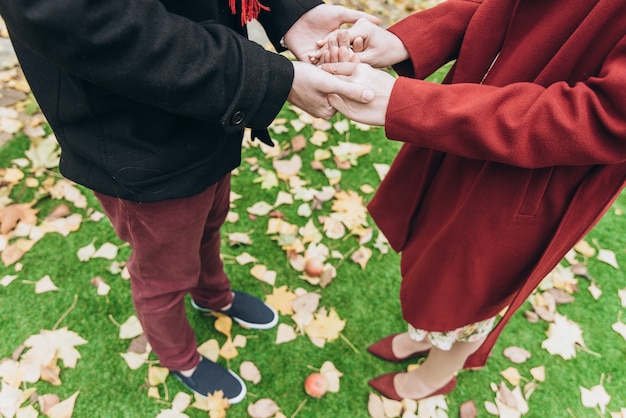 Cropped photo of the couple man and woman holding hands at the romantic date. Love outdoor lifestyle with nature on background