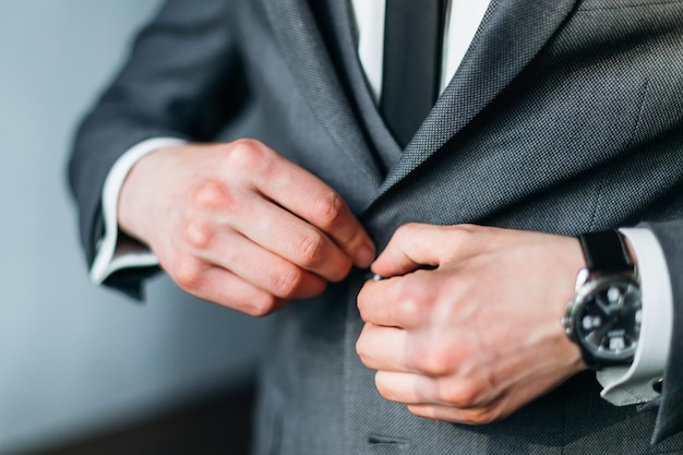 Cropped photo of elegant young fashion man dressing up for wedding celebration Groom dressed in modern blue business suit white shirt and tie prepares for an event