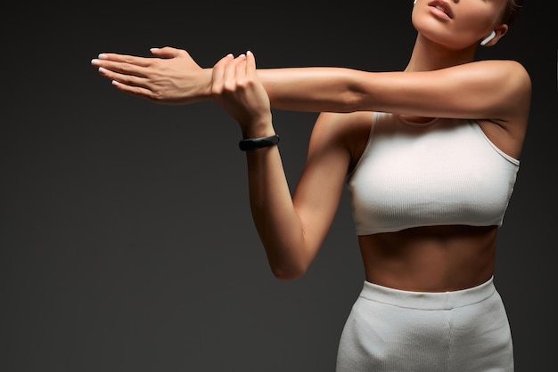 Cropped photo of a fitness woman stretching her hands isolated over grey background Copy space