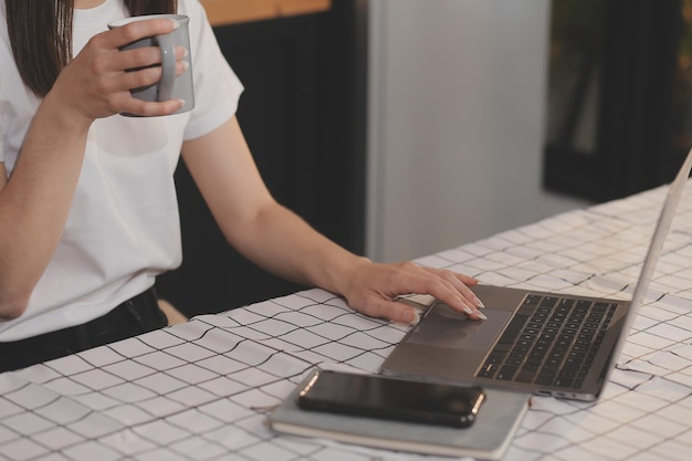 Cropped photo of Freelancer business Asian woman holding coffee cup and at doing planning analyzing the financial report business plan investment finance analysis the workplace