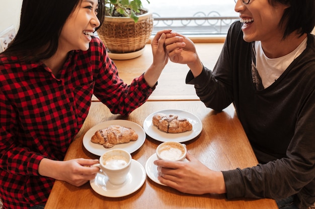 Cropped photo of happy young loving couple sitting in cafe