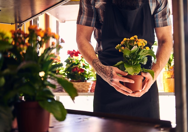 フラワーショップで働く制服を着た男性の花屋のトリミング写真。