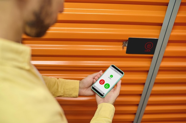 Cropped photo of male worker hands holding his phone next to the storage unit door