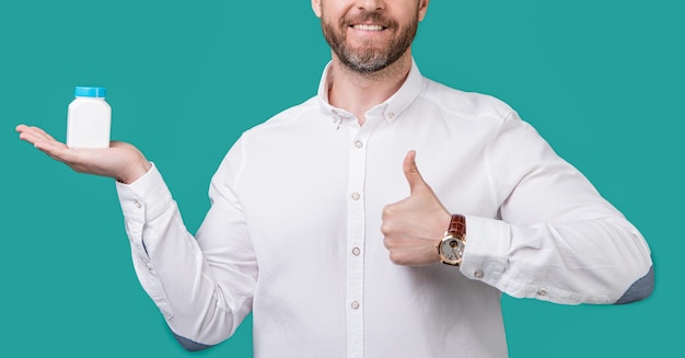 cropped photo of man holding medication healthcare man with medication isolated on blue background man hold medication in studio man presenting medication jar