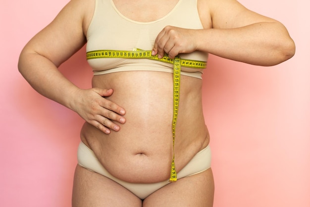 写真 裸の太りすぎの女性の体を保持し、ルーレットテープで測定している彼女の胸の胸の不健康な体のトリミングされた写真