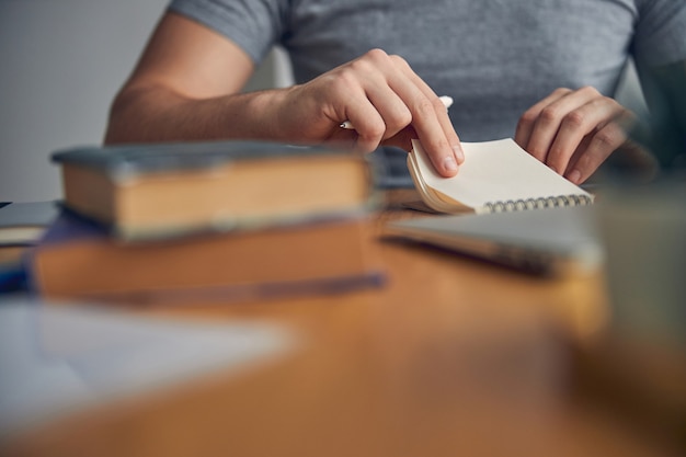 Cropped photo of person sitting and folding notebook while holding pen in hands