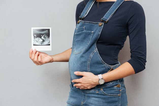 Cropped photo of pregnant woman showing ultrasound scans