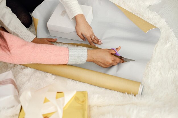 Cropped photo of two black girls wrapping a gift in a paper