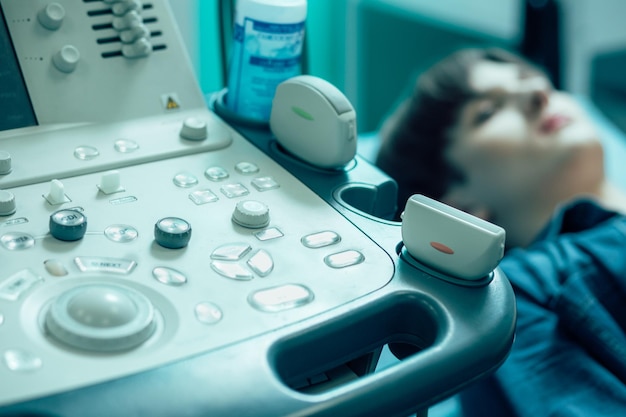 Cropped photo of an ultrasound scanner with two transducers. Male patient on the background