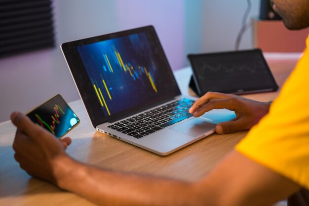 Foto foto ritagliata di un trader irriconoscibile che analizza i dati di investimento sulle criptovalute utilizzando laptop e tablet a casa