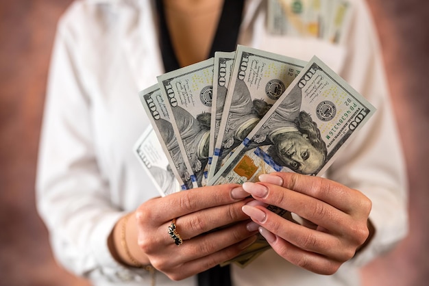 Cropped photo of a woman holding US dollar money in her hands on the background of her body