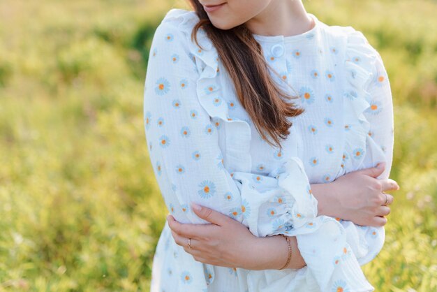 Photo cropped photo of a woman in a white dress hugging herself