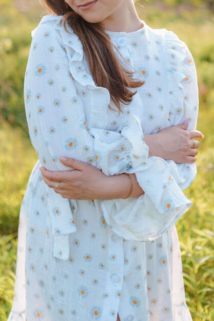 Photo cropped photo of a woman in a white dress hugging herself