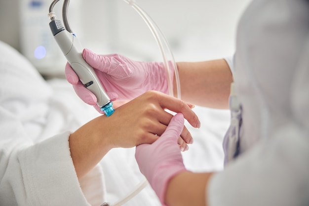 Cropped photo of a young dermatologist performing a skin rejuvenating procedure on a female hand