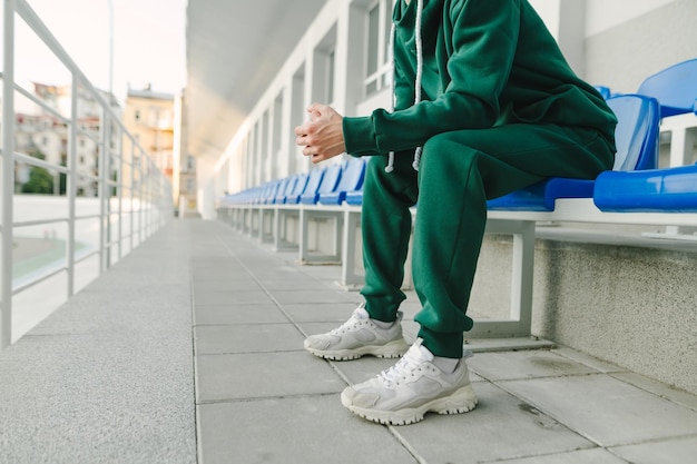 Cropped photo of a young man's legs in a green suit and bloodsuckers sitting alone