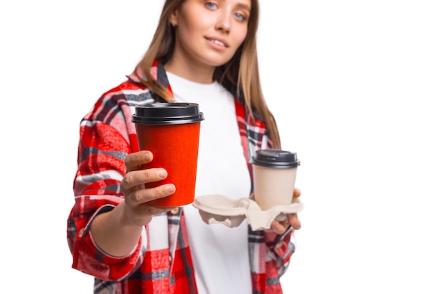 2杯のコーヒーのテイクアウトのうちの1杯をあなたに与える若い女性のトリミングされた写真。