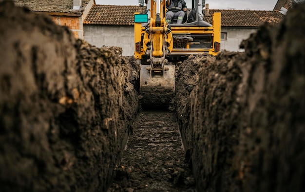 Cropped picture of a backhoe digging soil and making foundation at construction site