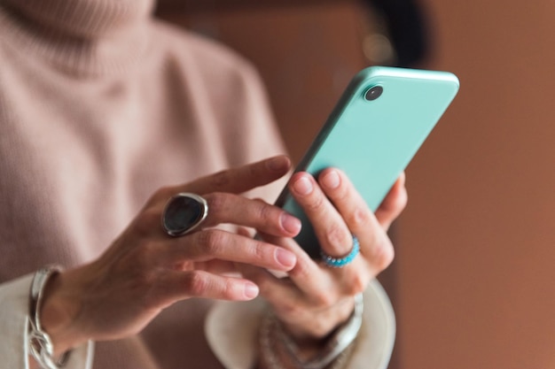 cropped picture fashion woman in brown sweater holding smartphone