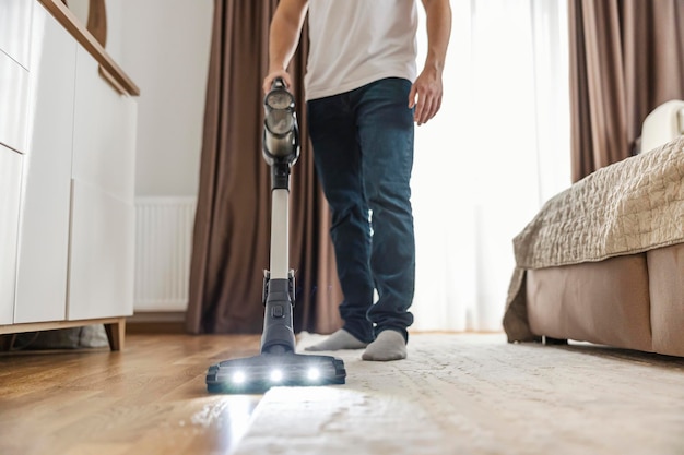 Обрезанное изображение мужчины, выполняющего работу по дому и пылесосящего дома