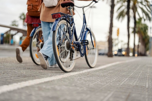 Обрезанное изображение двух человек, толкающих свои велосипеды на городской улице.