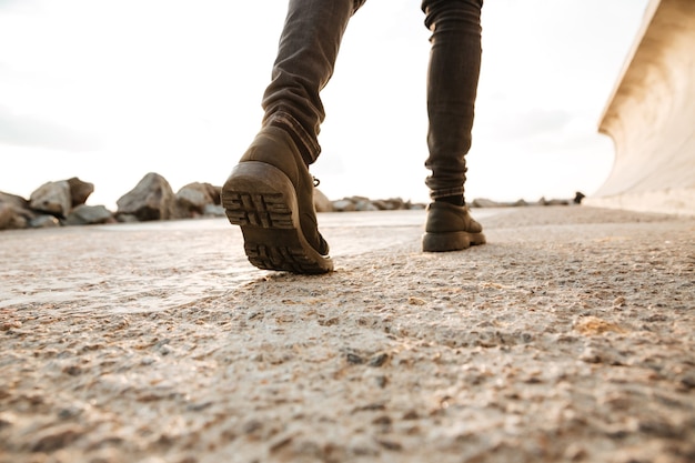 Cropped picture of young man walking on the beach.