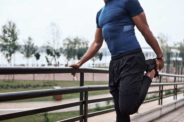 Cropped portrait of an african sportive man who is stretching legs