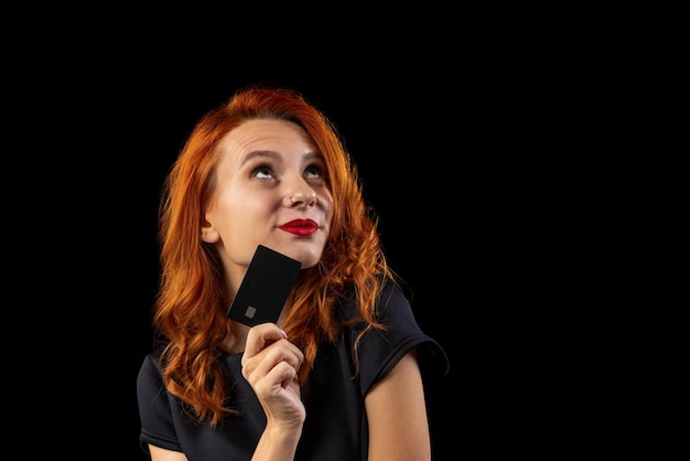 Cropped portrait of excited woman holding credit card isolated over black background online shopping