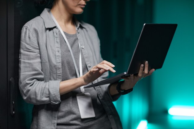 Photo cropped portrait of female data engineer holding laptop while working with supercomputer in server room, copy space