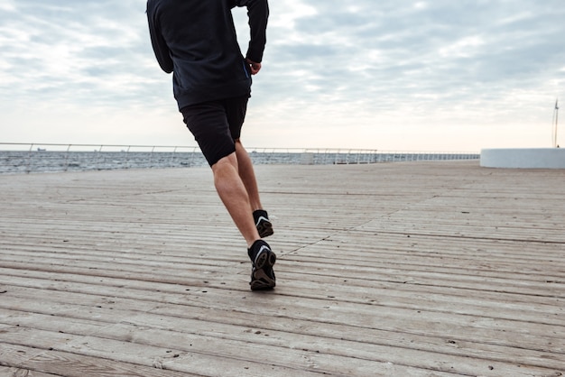 Cropped portrait of fitness man back view near the sea