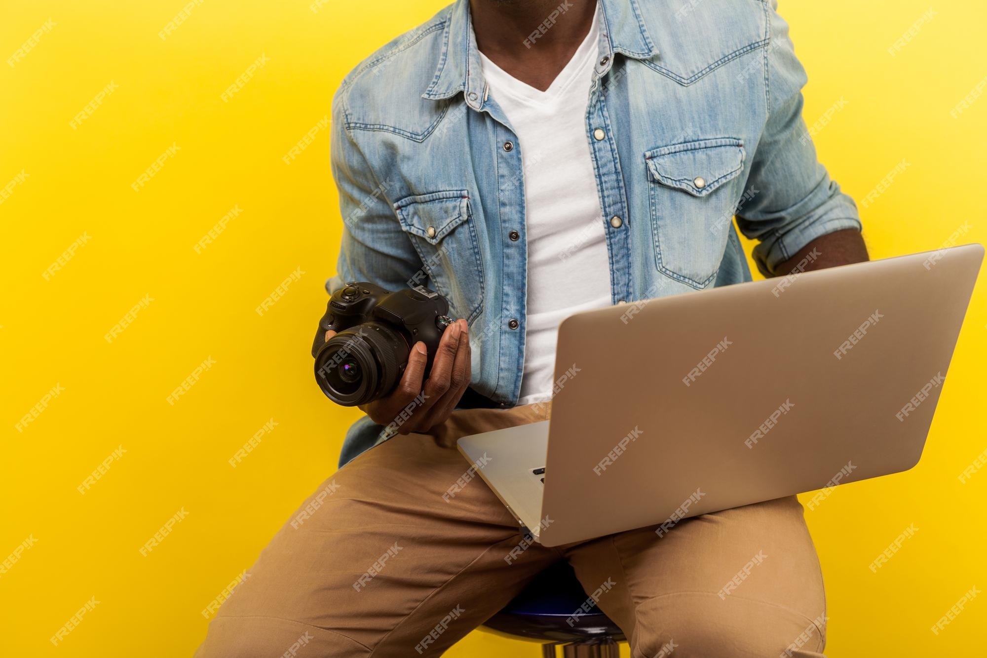 Premium Photo | Cropped portrait of male photographer in denim shirt  holding digital dslr camera and laptop, going to take picture or create  video, using photo editing apps. studio shot isolated on