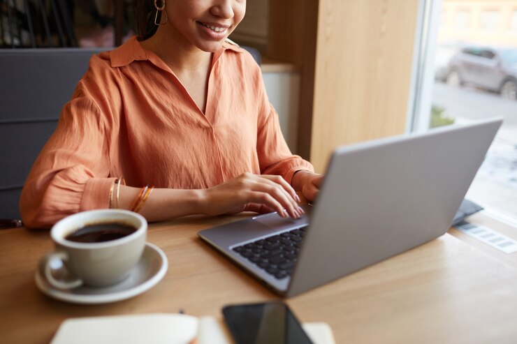 Photo cropped portrait of smiling young businesswoman using laptop while enjoying work at cafe table, copy space