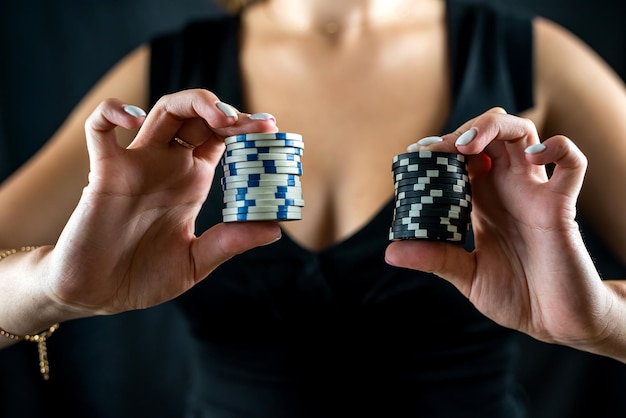 Photo cropped portrait of woman in black dress holding chips in front of cleavage for gambling