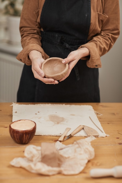 Ritratto ritagliato di una giovane artigiana che modella l'argilla mentre realizza una ciotola di ceramica in un laboratorio di ceramica, copia spazio